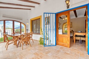 A dining area with a round table and chairs, a blue gate, and a view of the outdoors. - Villa 'Nichola' with Private Pool, Wi-Fi and Air Conditioning (Xàbia)