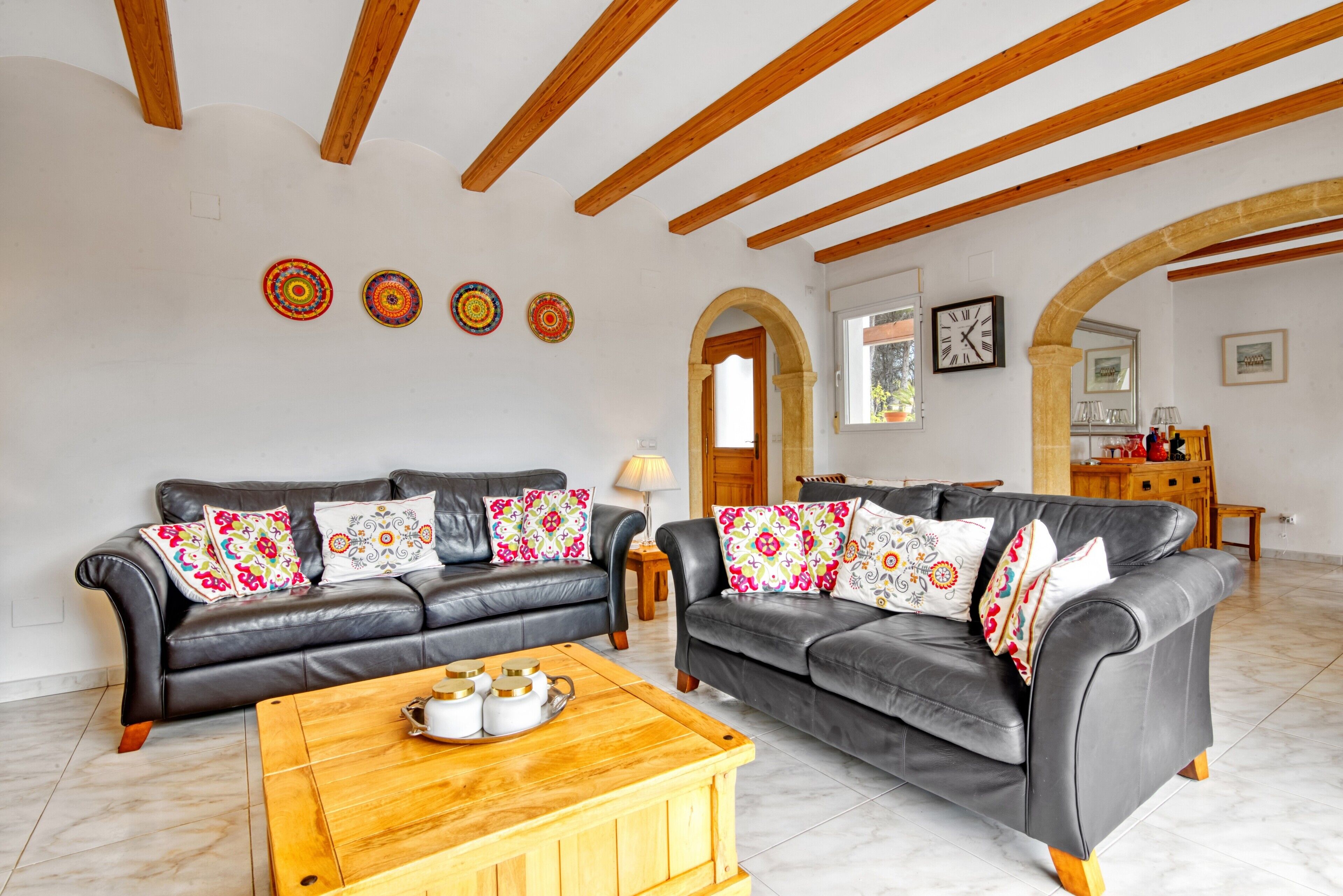 A living room with two leather sofas, a wooden coffee table, and a decorative wall with four circular patterns.