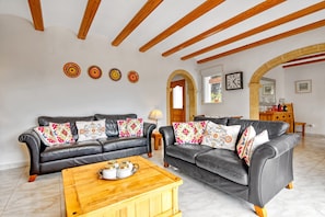 Una sala de estar con dos sofás de cuero, una mesa de centro de madera y una pared decorativa con cuatro diseños circulares.