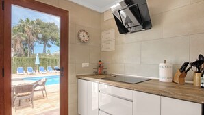 A kitchen with a view of a pool, wicker furniture, and a clock on the wall. - Villa 'Nichola' with Private Pool, Wi-Fi and Air Conditioning (Xàbia)