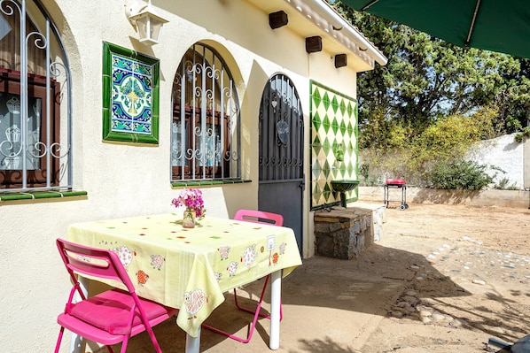 A patio with a table and chairs, a decorative wall, and a door with a heart-shaped decoration.