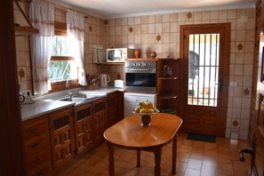 A kitchen with wooden cabinets, a sink, a stove, and a microwave. - Villa 'Vicenta' with Private Pool, Wi-Fi and Air Conditioning (Jávea)