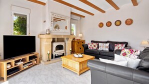 A living room with a fireplace, television, sofa, and wooden coffee table.