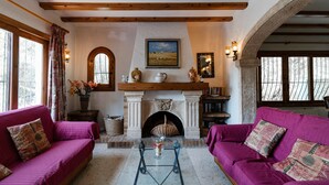 A cozy living room with two sofas, a fireplace, and a large window. - Villa 'Rosa' with Private Pool, Shared Terrace and Wi-Fi (Jávea)