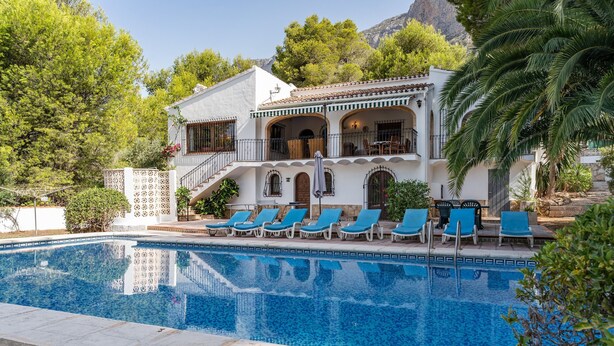 A poolside view of a building with a pool, lounge chairs, and a staircase leading to an upper level. - Villa 'Rosa' with Private Pool, Shared Terrace and Wi-Fi (Jávea)