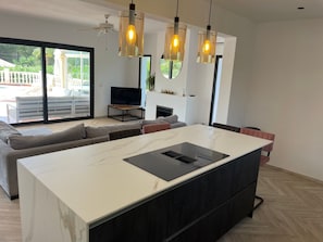 Uma sala de estar moderna com uma ilha grande, uma televisão e uma lareira.
