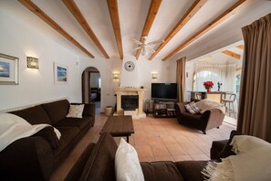 A living room with a fireplace, a television, and a dining area with a table and chairs. - Villa 'Sol' with Mountain View, Wi-Fi and Air Conditioning (Alicante)
