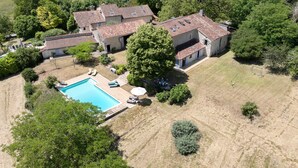 Vue aérienne d’une propriété comprenant une piscine, plusieurs bâtiments et une végétation luxuriante.