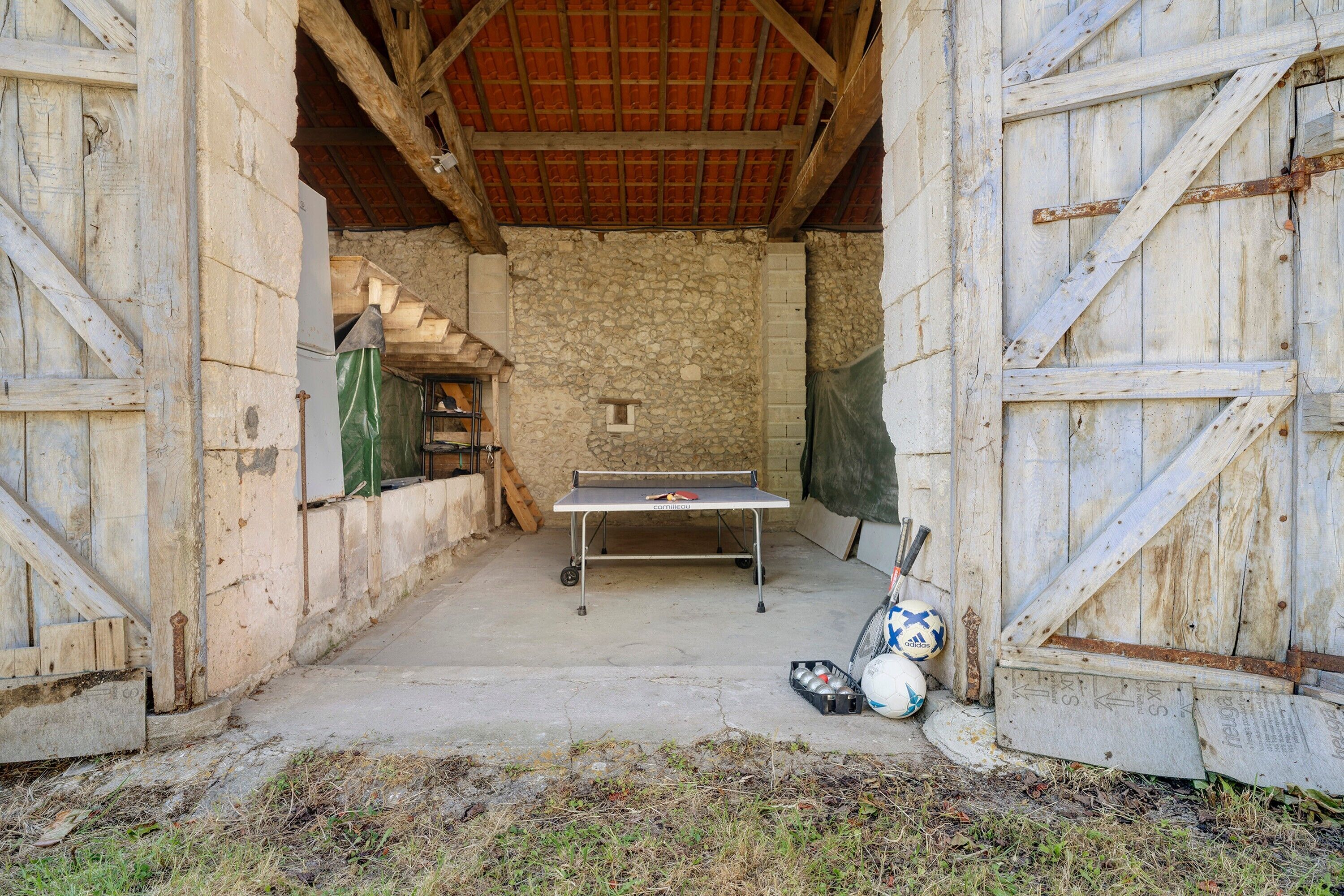 A rustic room with a ping pong table, a small window, and a door.