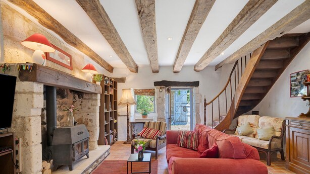 Un salon chaleureux avec une cheminée, des étagères à livres, un canapé et un escalier.