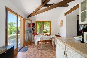 Une cuisine équipée d’une table à manger, d’un réfrigérateur et d’une fenêtre donnant sur un espace verdoyant.