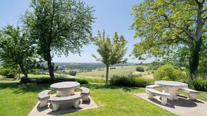 Une table de pique-nique installée dans un espace verdoyant, offrant une vue panoramique sur des collines ondulantes à l’arrière-plan.