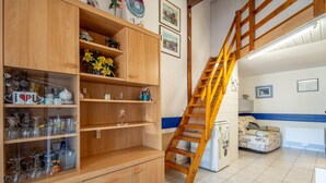 A kitchen with wooden cabinets, a built-in wine rack, a ladder leading to a loft, and a refrigerator. - Holiday Home 'Les Eaux Vives 1' with Sea View, Shared Pool and Private Terrace (Fleury)