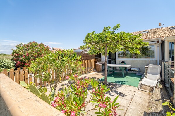 A patio with a table and chairs, a wooden fence, and a cactus plant.