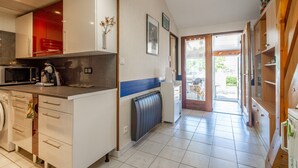 A modern kitchen with a microwave, oven, and sink. There is a hallway leading to a door. - Holiday Home 'Les Eaux Vives 1' with Sea View, Shared Pool and Private Terrace (Fleury)