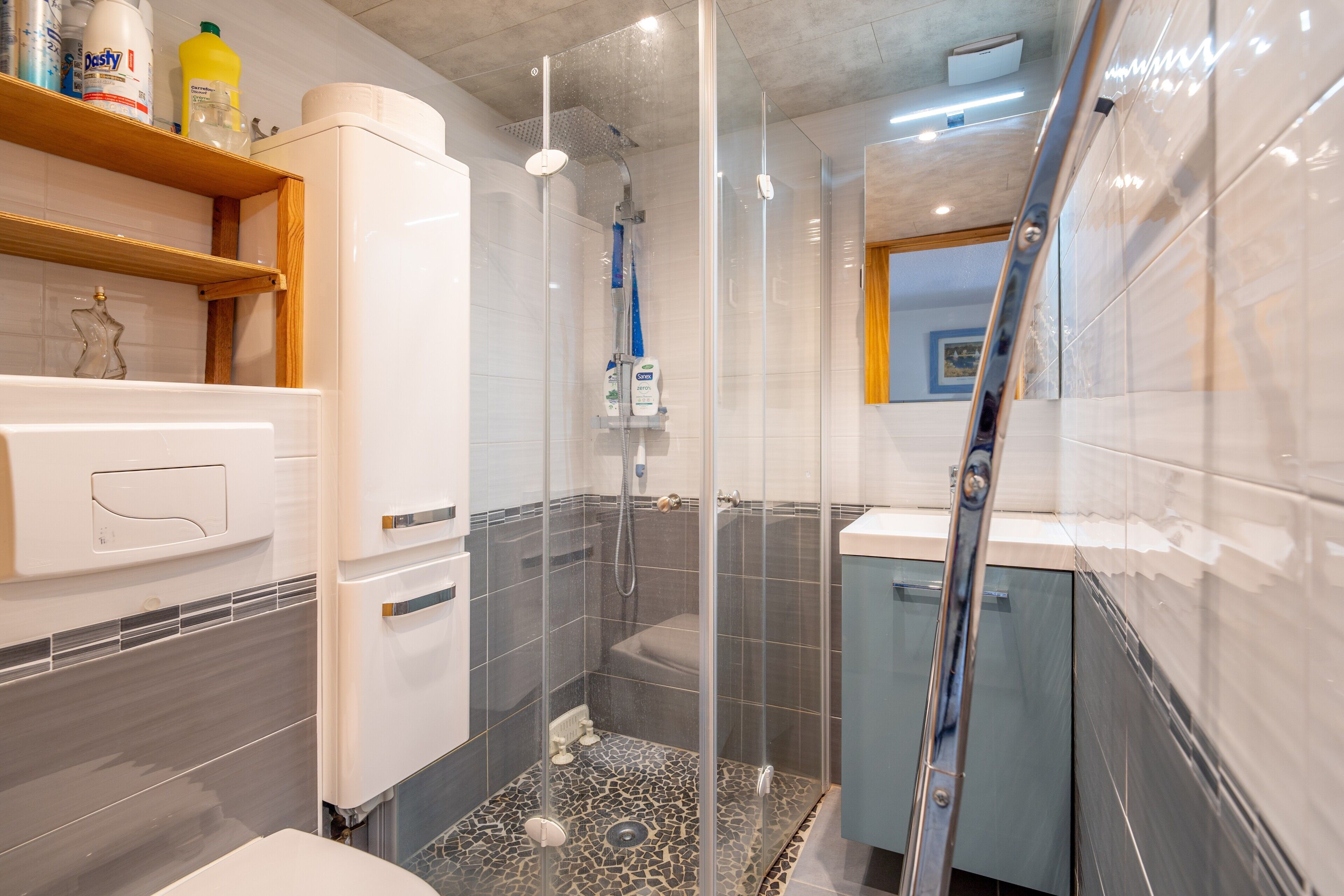 A modern bathroom with a glass-enclosed shower, a white sink, and a tiled floor.