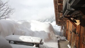 A wooden building with a snow-covered exterior, a wooden bench, and a wooden walkway leading to the entrance.