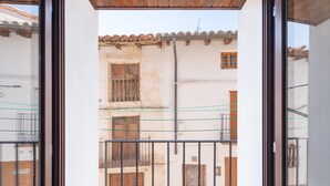On aperçoit, à travers une porte vitrée, un bâtiment doté d’un toit en tuiles, d’une porte en bois et d’un portail en métal.