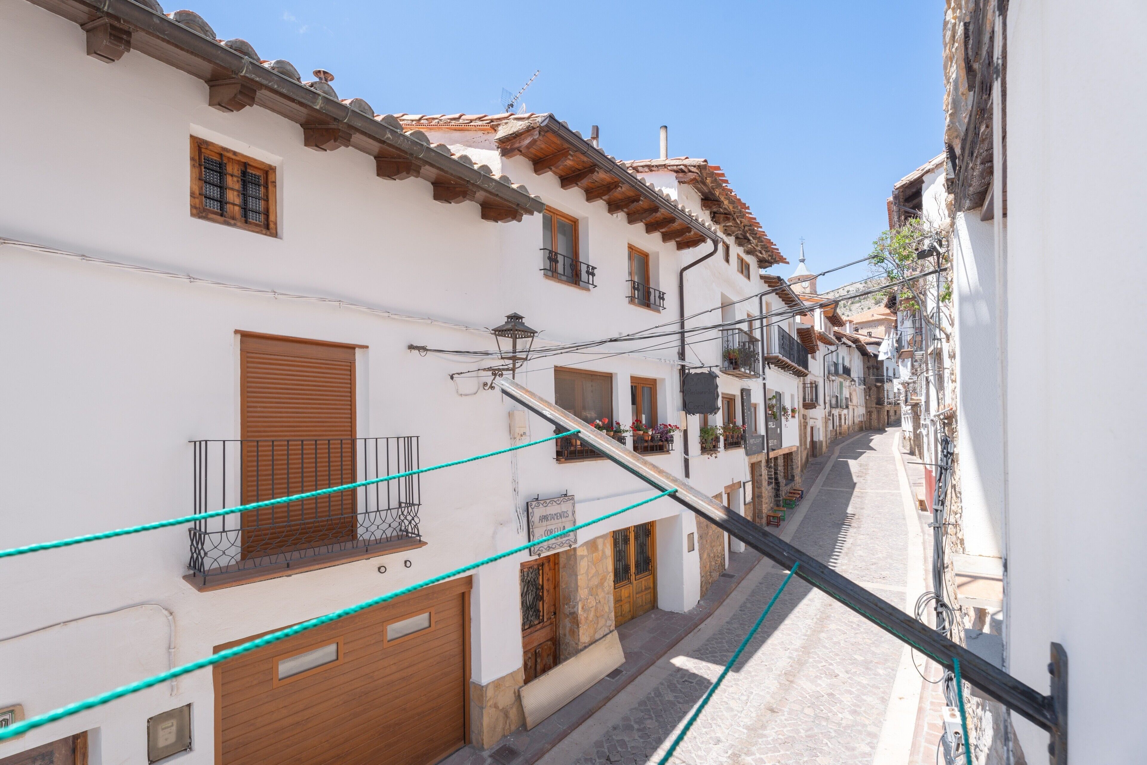 Una calle estrecha con edificios blancos, contraventanas de madera y balcones.