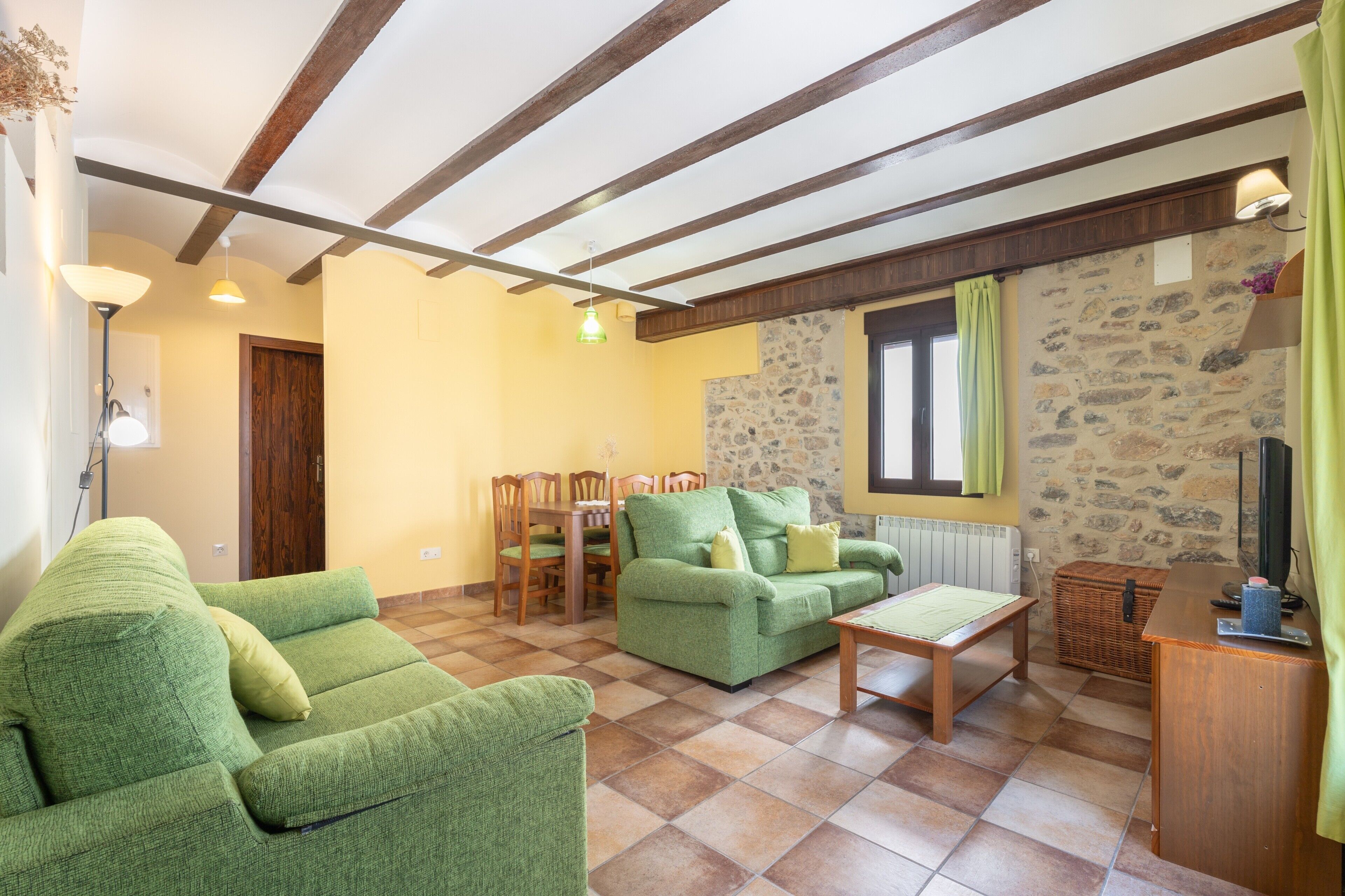 Un soggiorno con un divano verde, un tavolino in legno e una parete in pietra.