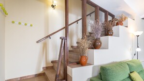 A staircase with a wooden handrail, a green sofa, and decorative vases on the landing.