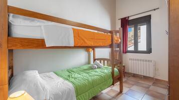 Dormitorio con literas, un edredón verde, un edredón blanco y una escalera de madera.