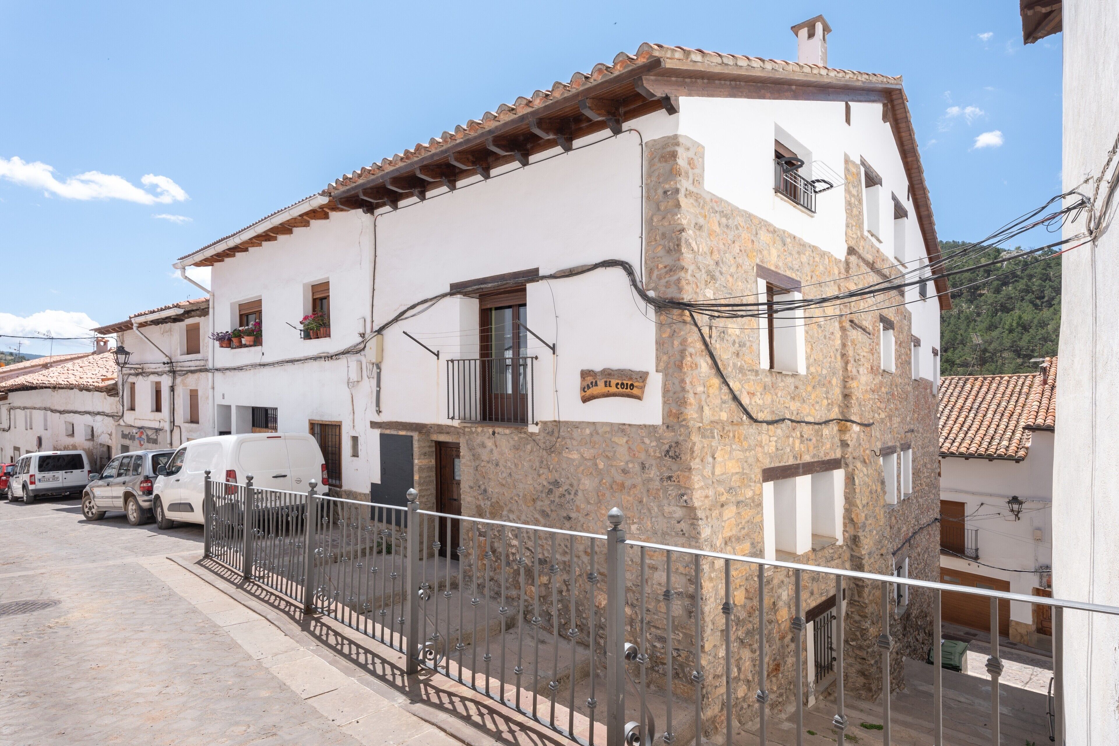 Un edificio blanco con fachada de piedra, un letrero que dice 'Casa del Colmo' y una cerca de metal al frente.