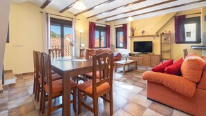 Un comedor con una mesa y sillas de madera, un sofá, un televisor y una chimenea.
