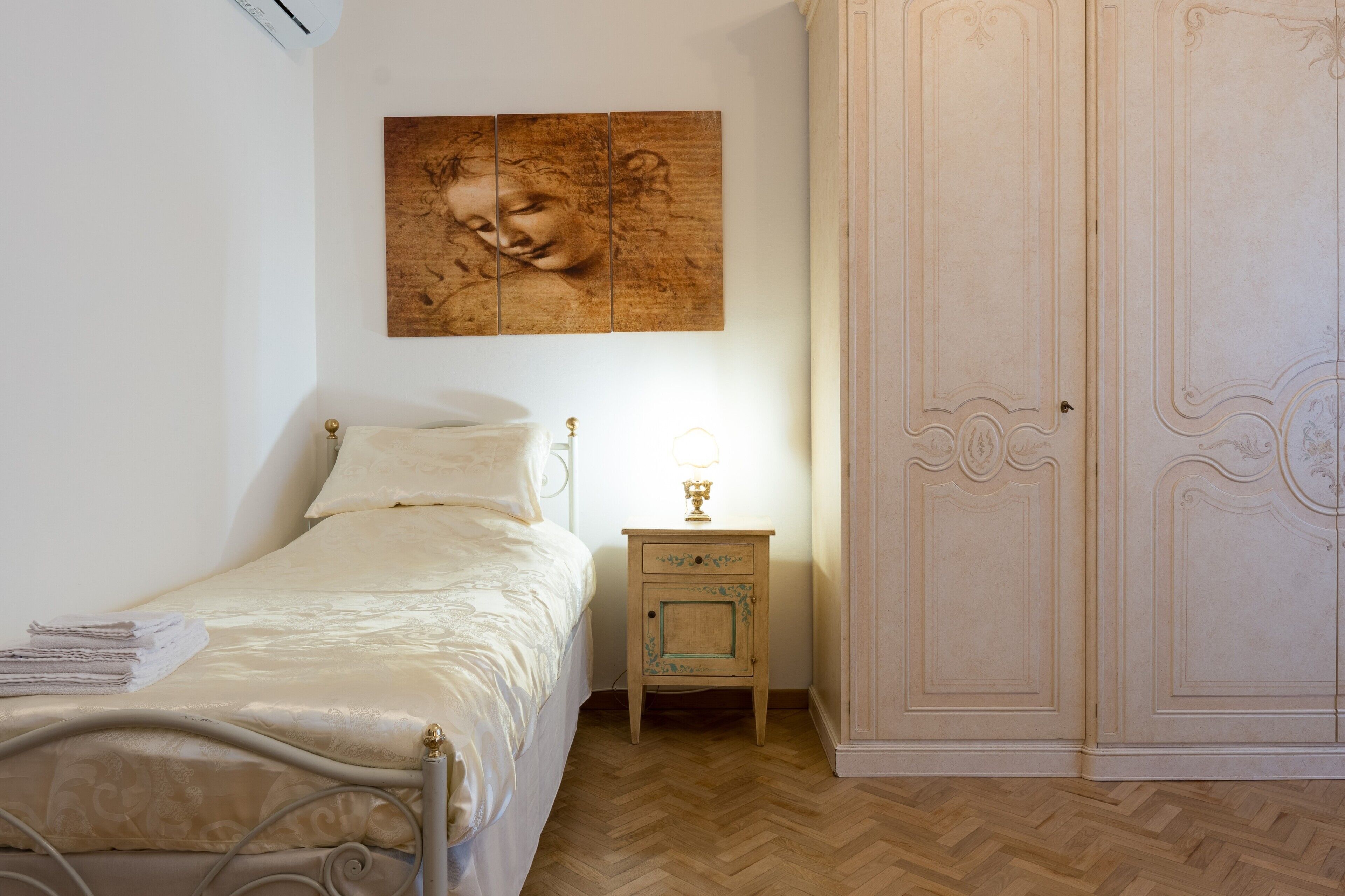 A bedroom with a bed, nightstand, and wardrobe.
