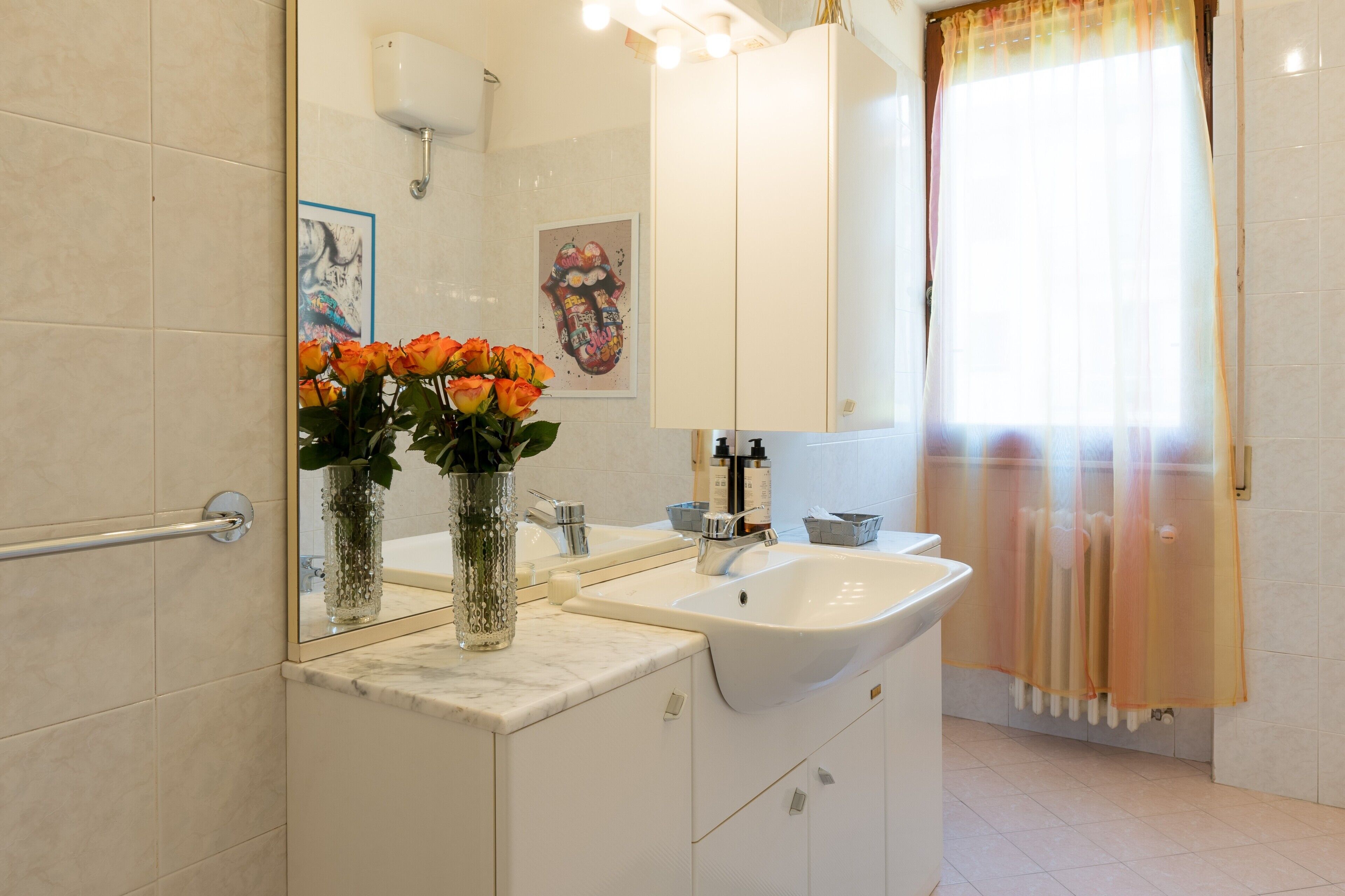 Un baño con lavamanos blanco, espejo, toallero y cortina de ducha.