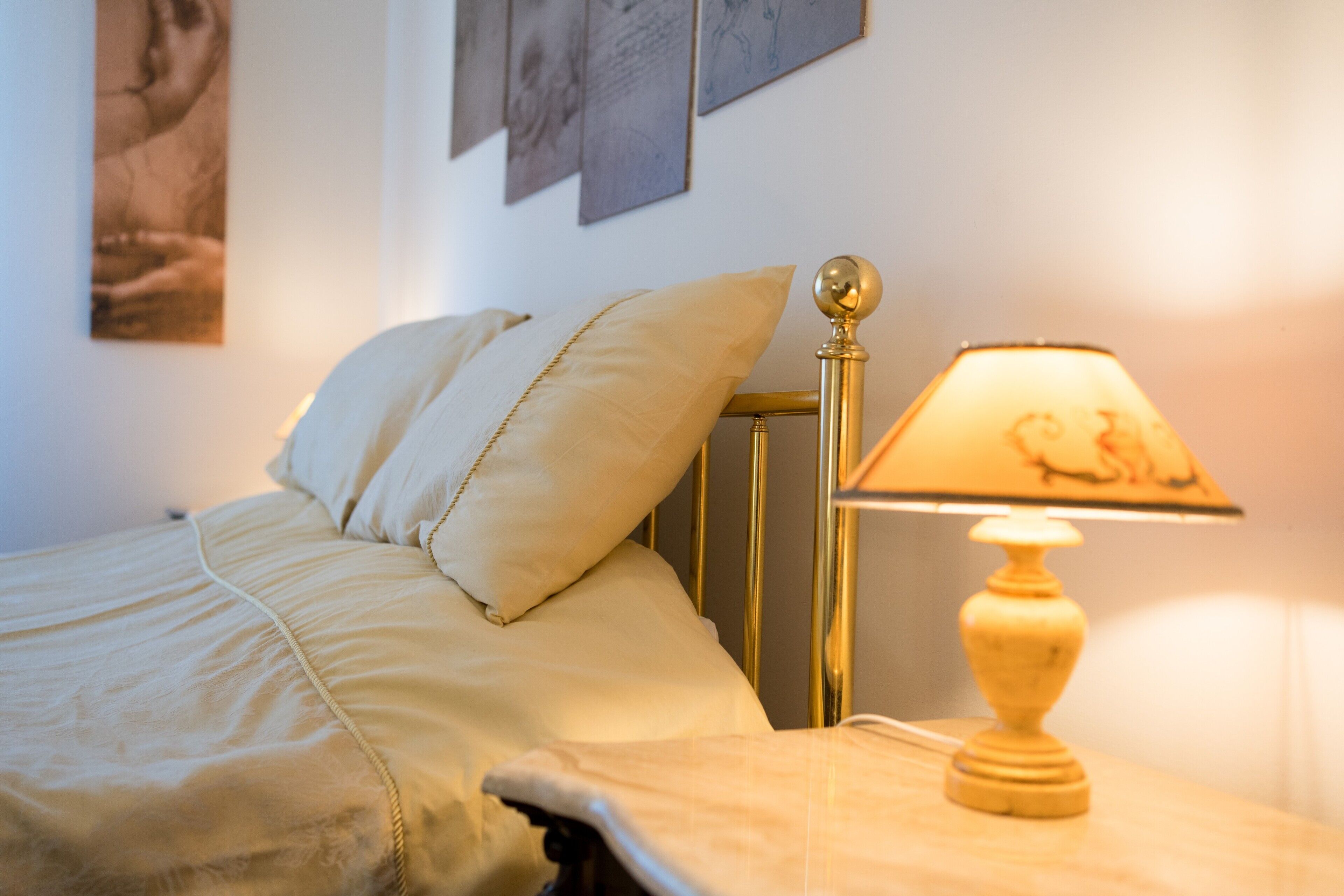 A bed with a headboard, a bedside lamp, and wall art.