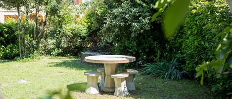 A garden with a round stone table and four matching stools.