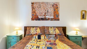 A bed with a patterned bedspread, two bedside tables with lamps, a wall with a framed artwork, and a small table with a decorative item. - 'Art Rooms - Banksy Klimt' Rooms with Shared Terrace, Wi-Fi and Air Conditioning (Arezzo)