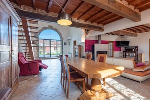 A spacious living area with a wooden dining table, red chairs, a sofa, and a TV. - Spacious House in Marciac with Private Pool and Terrace (Marciac)