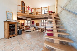 A spacious living area with a wooden staircase, a fireplace, and a dining area. - Spacious House in Marciac with Private Pool and Terrace (Marciac)