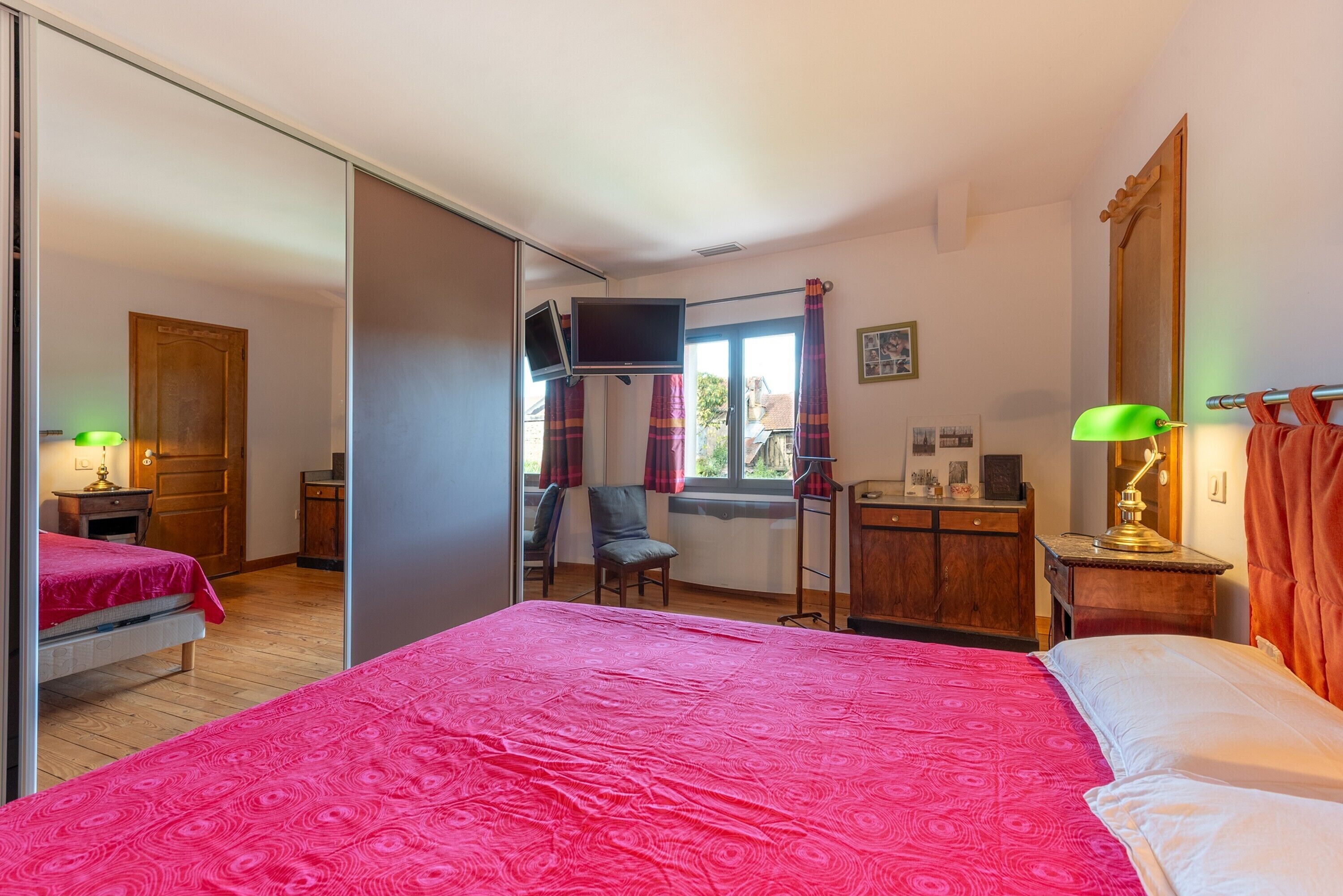 Quarto com cama, televisão, escrivaninha e cadeira.