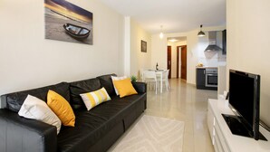 A living room with a black sofa, a flat-screen TV, and a painting of a boat on the wall.