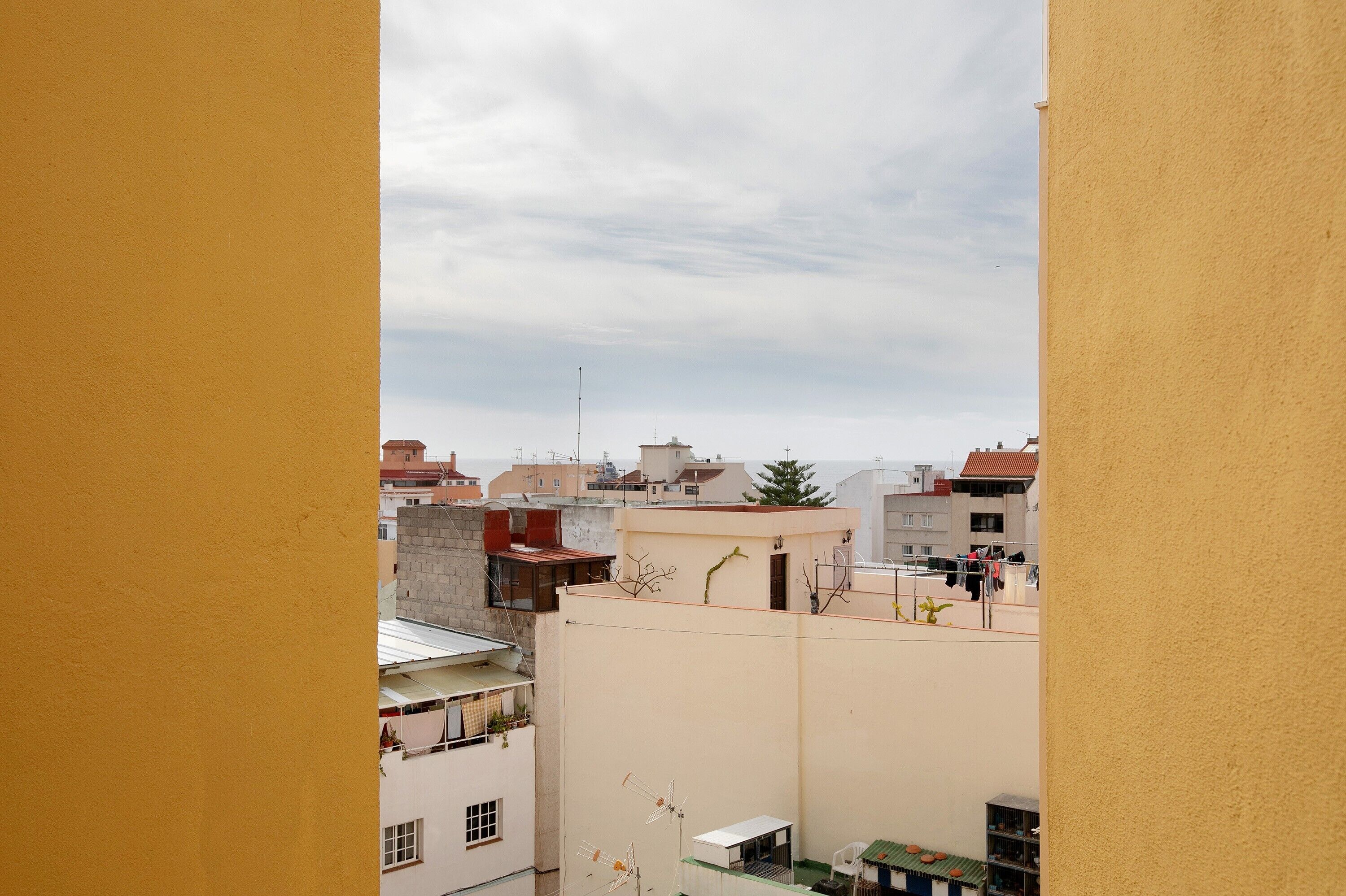 Vista de una zona residencial con edificios, algunos con balcones y antenas parabólicas, bajo un cielo nublado.