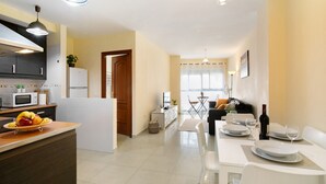 A modern kitchen with a dining area, white appliances, and a clear view into the living room.