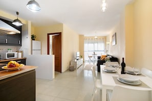 Eine moderne Küche mit Essbereich, weißen Geräten und freiem Blick in das Wohnzimmer.