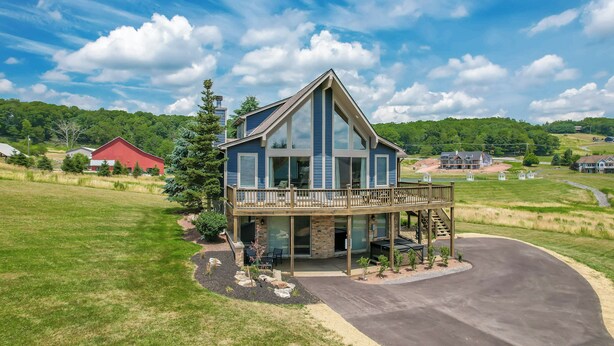 Une maison moderne à deux étages, dotée d’une grande terrasse, de fondations en pierre et d’une pelouse bien entretenue.