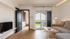 Un salon moderne doté d’un téléviseur à écran plat, d’un canapé, d’une table basse et d’une porte-fenêtre coulissante donnant sur un espace extérieur.
