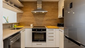 Une cuisine moderne dotée d’un four encastré, d’appareils électroménagers en acier inoxydable et d’un pare-feu en bois.