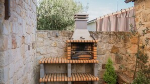 A stone wall with a brick oven, wooden benches, and a potted plant. - Country House 'Entrada Rio Lobos 2' with Mountain Views and Wi-Fi (Hontoria del pinar)