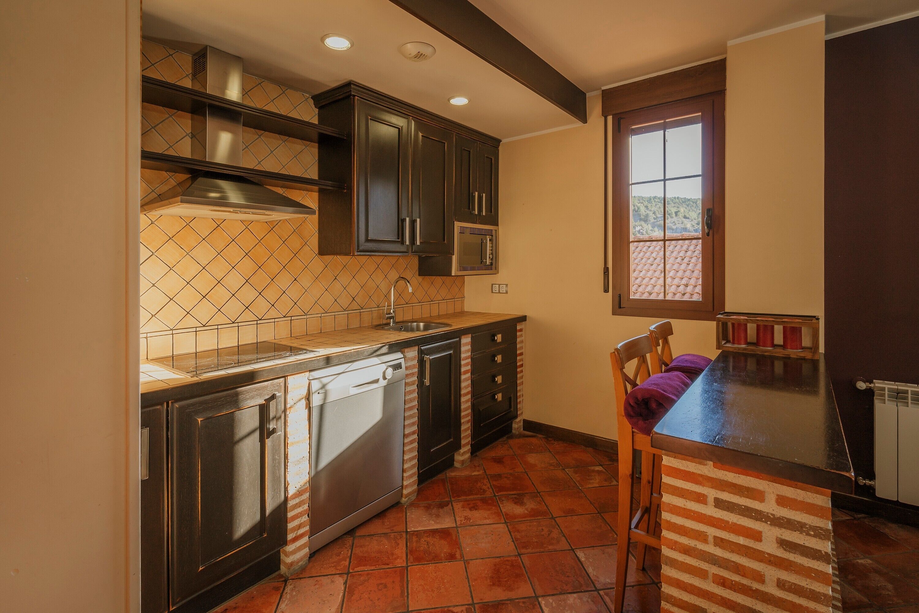 A kitchen with a dishwasher, a microwave, and a window with a view.