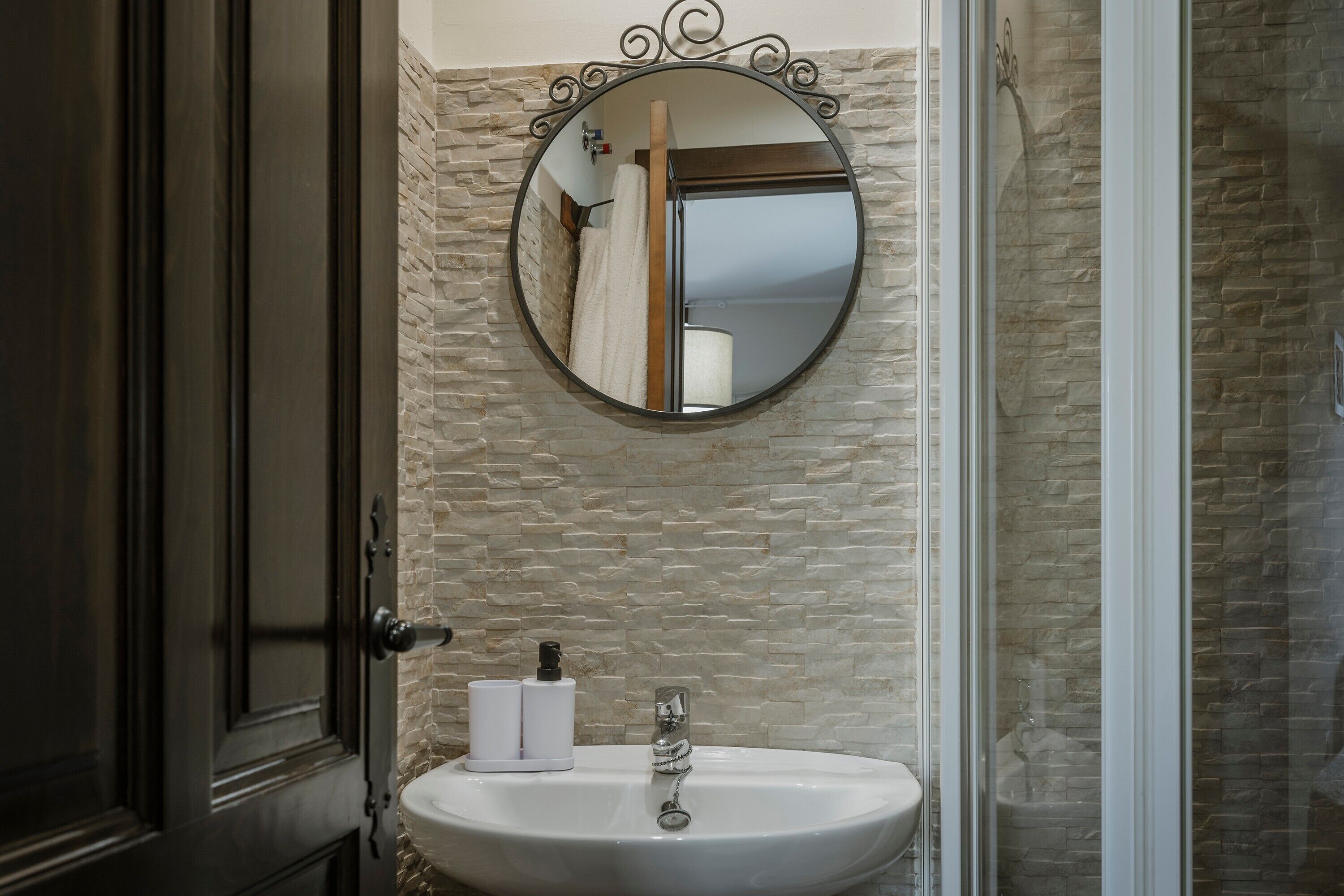 Une salle de bain avec un miroir rond, un lavabo et un porte-serviettes.