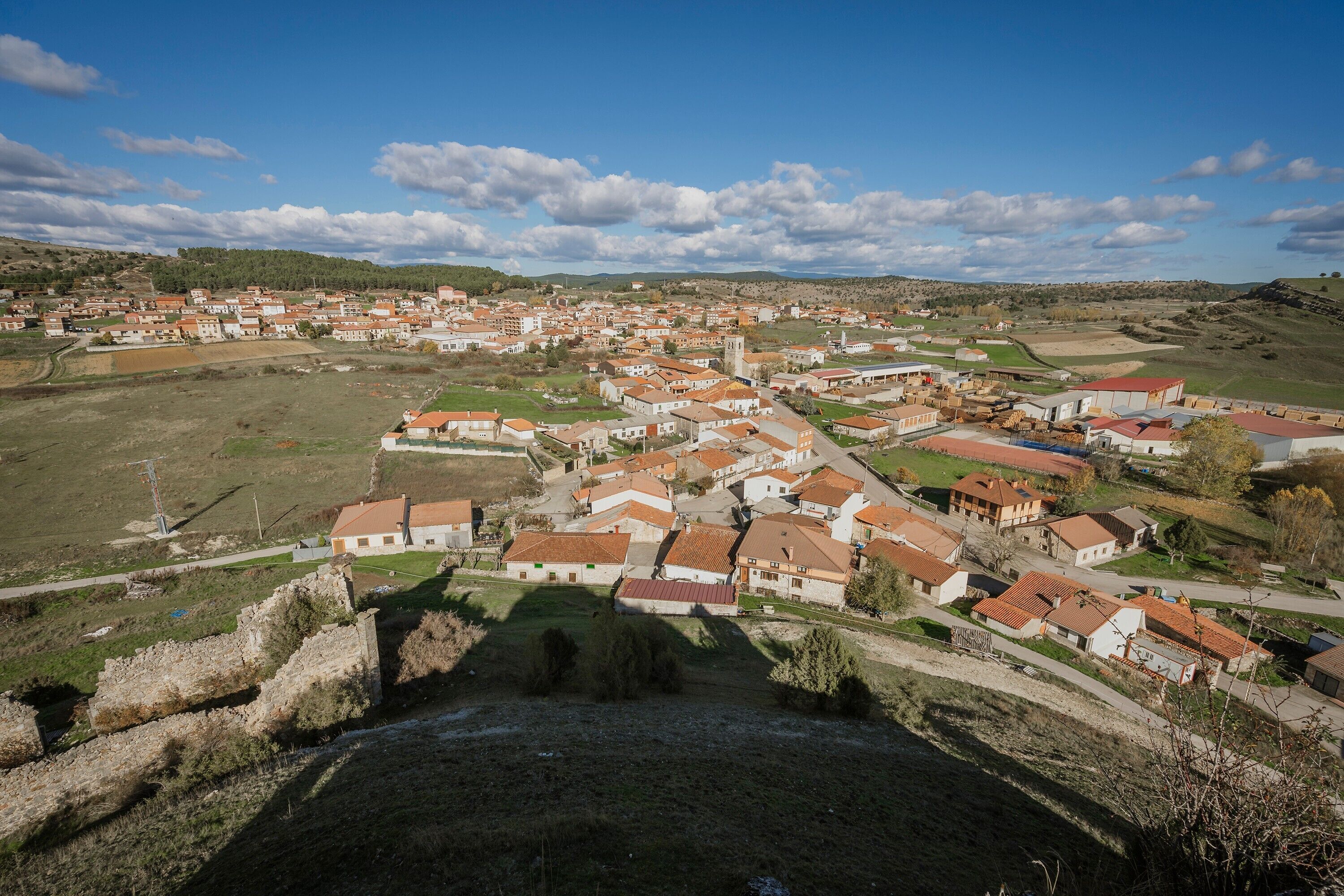 A town with a central square, buildings with red-tiled roofs, and a prominent church tower.