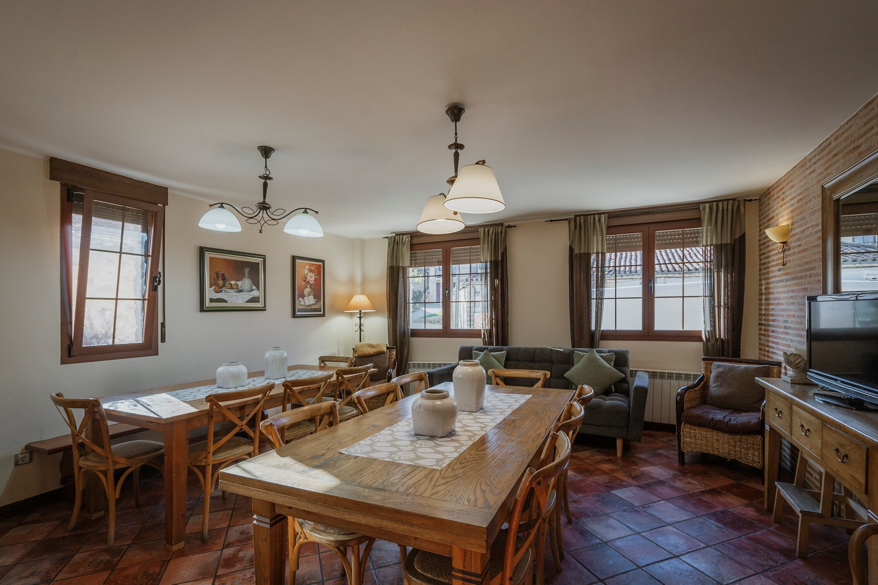 A dining area with a wooden table, chairs, and a television on a wooden cabinet.
