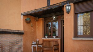 A wooden bench outside a building with a brick wall, a window, and hanging planters. - Country House 'Entrada Rio Lobos I' with Mountain Views, Private Terrace and Wi-Fi (Hontoria Del Pinar)