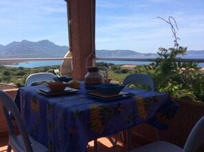 An outdoor dining area with a table set for two, overlooking a scenic view of a body of water and mountains. - Apartment 'La Terrazza Sulla Baia Di Calvi' with Sea View, Private Terrace and Private Garden (Lumio)